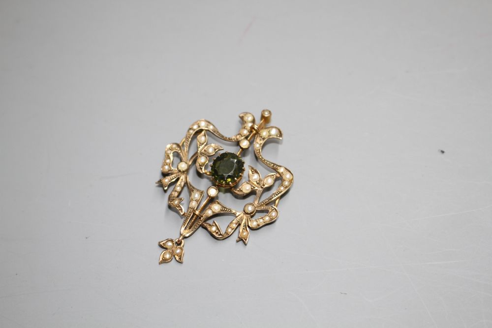 An Edwardian 9ct, green garnet and seed pearl set openwork scroll drop pendant,